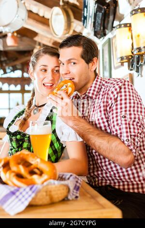 Bayerischen paar tragen traditionelle Kleidung, flirten und trinken Bier im restaurant Stockfoto