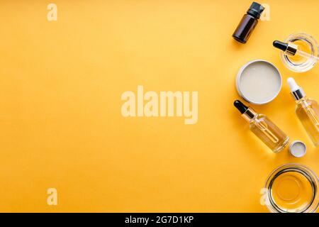 Verschiedene Arten von kosmetischen Ölen in Glas und Metall Gläser Flaschen Tropf, ätherisches Öl, Serum, Butter für die Hautpflege und Kosmetik Behandlung auf gelb Stockfoto