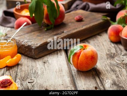 Still Life Pfirsiche auf Holztisch mit Schneidebrettmesser in dunklem Schlüssel. Saftig reife Pfirsiche auf dunklem rustikalem Holztisch. Köstliche Bauernpfirsiche mit Stockfoto