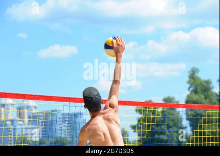 Beachvolleyball. Männlicher Volley-Spieler trifft über den Netzball angreifend. Stockfoto