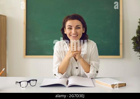Webcam-Porträt einer glücklichen Lehrerin, die während ihres Online-Unterrichts an ihrem Schreibtisch sitzt Stockfoto