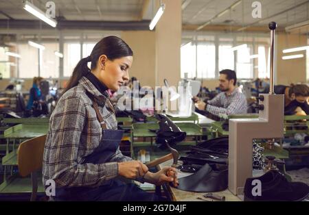 Porträt einer jungen Schuhmacherin, die am Arbeitsplatz in der Schuhfabrik arbeitet Stockfoto