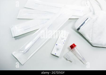 Schnellantigen-Selbsttest-Kit für die Covid-19-Diagnose zu Hause mit Nasenabstrichbestrichen, Röhrchen, Detektionsgerät und ffp-2-Gesichtsmaske, hellgrauem Hintergrund, CO Stockfoto