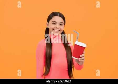 Fröhliches Kind mit Kaffeetasse zum Mitnehmen auf gelbem Hintergrund, guten Morgen Stockfoto