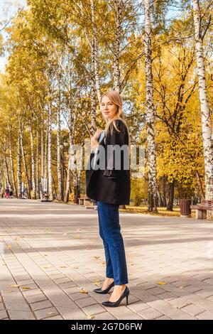 Geschäftsfrau in schwarzem Blazer im Park. Herbstpark, sonniger Tag. Stockfoto