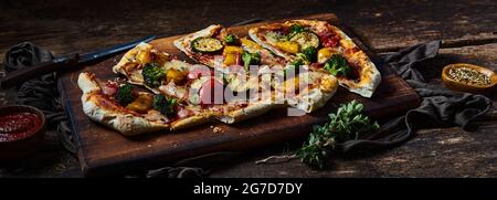 Von oben von leckeren hausgemachten Pizza mit Gemüse serviert auf Holz Schneidebrett in der Küche Stockfoto