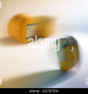 Gelbe Schraubverschlüsse aus Aluminium und Kunststoff für Flaschen in Bewegung verschwimmen auf hellem Hintergrund, abstraktes Konzept für nachhaltige Produktion und vermeiden Stockfoto