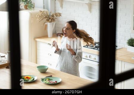 Junge Frau mit gemischter Rasse, die mit einem Schläger wie einem Mikrofon singt Stockfoto