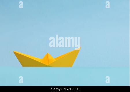 Konzeptionelles Boot aus gelbem Papier auf blauem Hintergrund Stockfoto
