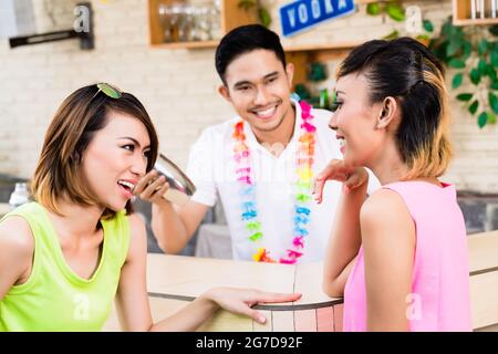 Seitenansicht von zwei jungen Frauen, die an der Theke sitzen Stockfoto
