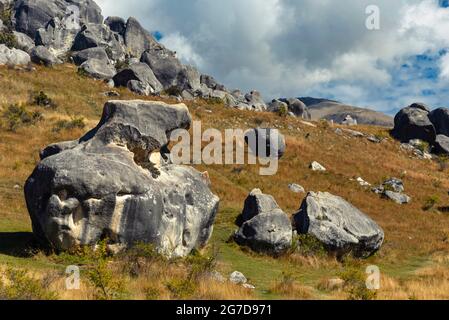 Atemberaubende Felsbrocken auf Castle Hill, Neuseeland. Blauer, wolkig bewachsener Himmel, goldenes Grasland, die Berge der südlichen alpen umraenkend. Arthur's Pass Stockfoto