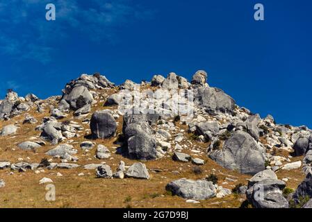 Atemberaubende Felsbrocken auf Castle Hill, Neuseeland. Blauer, wolkig bewachsener Himmel, goldenes Grasland, die Berge der südlichen alpen umraenkend. Arthur's Pass Stockfoto