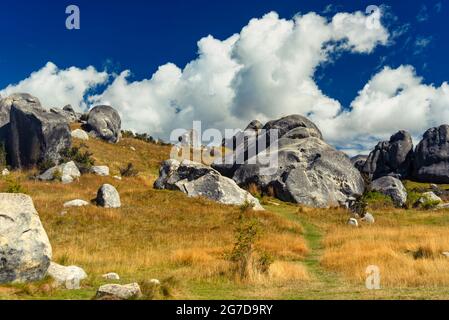 Atemberaubende Felsbrocken auf Castle Hill, Neuseeland. Blauer, wolkig bewachsener Himmel, goldenes Grasland, die Berge der südlichen alpen umraenkend. Arthur's Pass Stockfoto