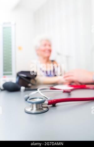Arzt mit Rentner in Chirurgie Sprechstunde am Schreibtisch saß Stockfoto