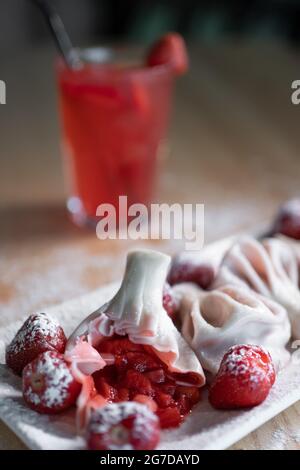 Süsse Knödel oder Khinkali mit Erdbeere und kalter roter Limonade auf dem Tisch Stockfoto