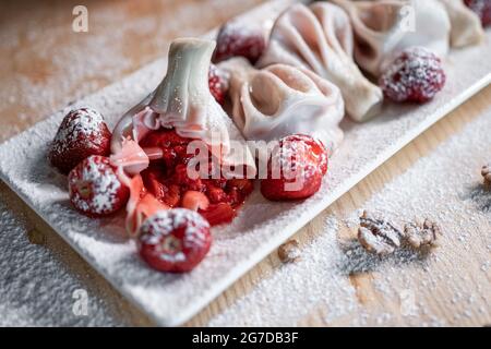 Süße Knödel oder Khinkali mit Erdbeere auf weißem Teller auf Holzgrund Stockfoto