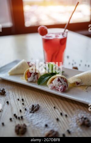 Pfannkuchenbrötchen mit Quark und Erdbeere und roter Limonade trinken Sie im Glas Stockfoto