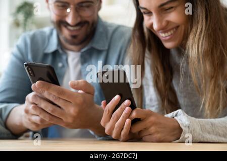 Lachendes Paar, das auf die Bildschirme von Smartphones schaut, konzentriert sich auf Gadgets Stockfoto