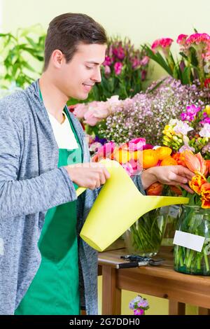 Floristen arbeiten im Blumengeschäft Pflanzen gießen Stockfoto