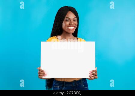 Fröhliche Schwarze Frau Zeigt Leere Poster Werbetext, Blauer Hintergrund Stockfoto