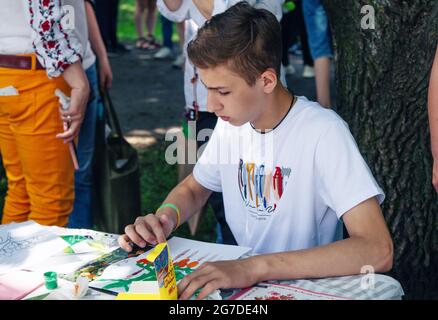 Zaporizhia, Ukraine- 19. Juni 2021: Charity Familienfest: Junge Teilnahme an Kunst und Handwerk im Freien Workshop, machen bunte Zeichnung mit Gouac Stockfoto