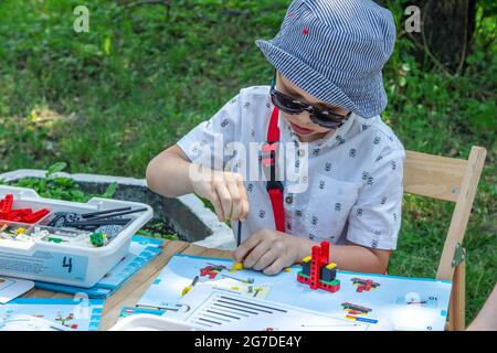 Zaporizhia, Ukraine- 19. Juni 2021:Charity Family Festival: Junge spielt mit Spielzeugkonstruktions-Design-Kit bei Kunst und Handwerk im Freien Workshop. Stockfoto