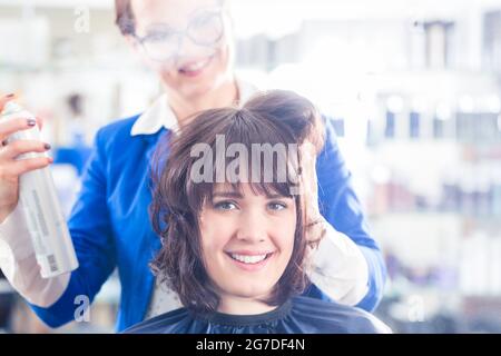 Weibliche Frisur geben Frauen Hairstyling mit Haarspray im Friseur-shop Stockfoto