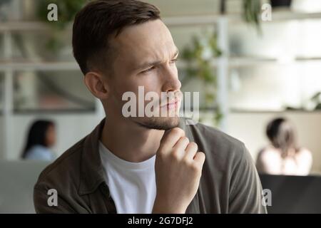 Ernst nachdenklicher junger Mann, Geschäftsmann, der das Fenster weg betrachtet Stockfoto