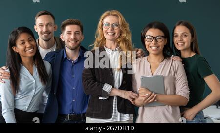 Glückliche unternehmerische reife Mentorin und multiethnische Gruppe von Praktikanten Stockfoto