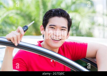 Asiatischer Mann zeigt Schlüssel seines neuen Autos Stockfoto