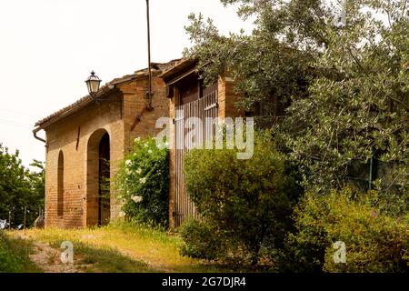 Schönes rotes Backsteinhaus in Italien, umgeben von Pflanzen und Blumen. Gemütliche idyllische Aussicht im rustikalen sonnigen Italia. Region Siena, Italien Stockfoto