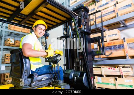 Asiatische Gabelstapler LKW Fahrer heben Palette in Lagerhalle Stockfoto