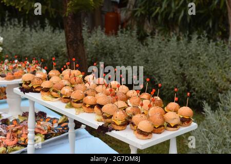 Viele leckere Burger auf dem Holztisch. Selbstbedienungsbuffet. Stockfoto