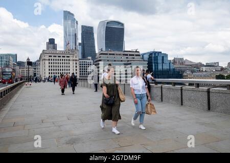 London, Großbritannien. 13. Juli 2021. Menschen auf der London Bridge in der City of London. Die britische Regierung hat angekündigt, die Sperrbeschränkungen am 19. Juli zu lockern. Unternehmen prüfen, ob sie alle Mitarbeiter wieder in ihre Büros zurückholen, weiterhin von zu Hause aus arbeiten oder zu einem hybriden Beschäftigungsmodell wechseln sollen. Kredit: Stephen Chung / Alamy Live Nachrichten Stockfoto