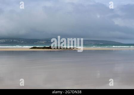 Stimmungsvolle Strandszene. Der Strand von Gwihian mit Blick auf St. Ives, Cornwall, an einem bewölkten Tag. Stockfoto