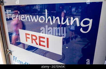 Zinnowitz, Deutschland. Juli 2021. Passanten gehen an einem Schild für kostenlose Ferienwohnungen vorbei. Viele Touristen genießen Sonne, Sand, Wellen und Meer am Strand auf der Insel Usedom. Quelle: Stefan Sauer/dpa/Alamy Live News Stockfoto