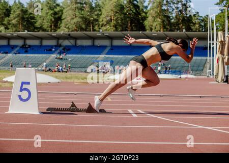 Junge Sprinterin läuft von Startblöcken bis zum Wettkampf Stockfoto