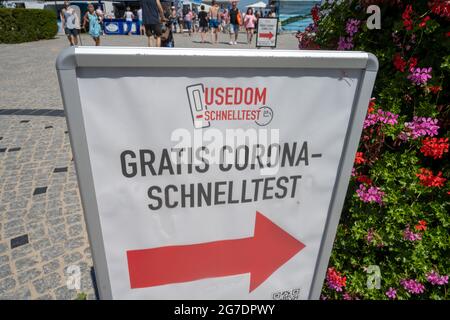 Zinnowitz, Deutschland. Juli 2021. Passanten gehen an einem Schild mit der Aufschrift „Free Corona Quick Test“ vorbei. Viele Touristen genießen Sonne, Sand, Wellen und Meer am Strand auf der Insel Usedom. Quelle: Stefan Sauer/dpa/Alamy Live News Stockfoto