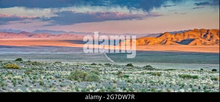 Unbefestigte Straße, die das Dugway Valley durchquert, virga-Luftschlangen verdunstenden Regens unter Wolken, Sonnenaufgang, vom Pony Express Trail, Great Basin, Utah, USA Stockfoto