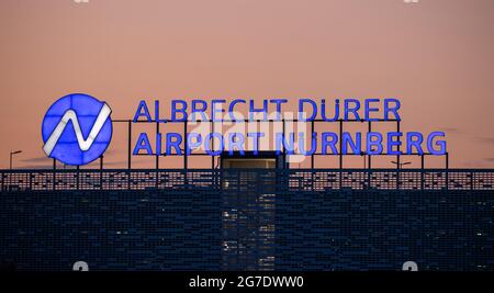 Nürnberg, Deutschland. Juli 2021. Auf dem Dach eines mehrstöckigen Parkhauses am Flughafen leuchtet abends der Schriftzug „Albrecht Dürer Airport Nürnberg“. Quelle: Daniel Karmann/dpa/Alamy Live News Stockfoto