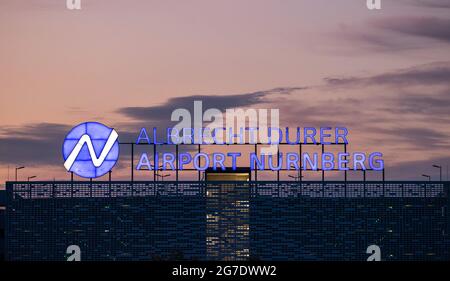 Nürnberg, Deutschland. Juli 2021. Auf dem Dach eines mehrstöckigen Parkhauses am Flughafen leuchtet abends der Schriftzug „Albrecht Dürer Airport Nürnberg“. Quelle: Daniel Karmann/dpa/Alamy Live News Stockfoto