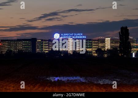 Nürnberg, Deutschland. Juli 2021. Auf dem Dach eines mehrstöckigen Parkhauses am Flughafen leuchtet abends der Schriftzug „Albrecht Dürer Airport Nürnberg“. Quelle: Daniel Karmann/dpa/Alamy Live News Stockfoto