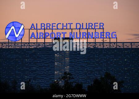 Nürnberg, Deutschland. Juli 2021. Auf dem Dach eines mehrstöckigen Parkhauses am Flughafen leuchtet abends der Schriftzug „Albrecht Dürer Airport Nürnberg“. Quelle: Daniel Karmann/dpa/Alamy Live News Stockfoto