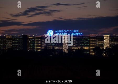 Nürnberg, Deutschland. Juli 2021. Auf dem Dach eines mehrstöckigen Parkhauses am Flughafen leuchtet abends der Schriftzug „Albrecht Dürer Airport Nürnberg“. Quelle: Daniel Karmann/dpa/Alamy Live News Stockfoto