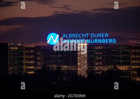 Nürnberg, Deutschland. Juli 2021. Auf dem Dach eines mehrstöckigen Parkhauses am Flughafen leuchtet abends der Schriftzug „Albrecht Dürer Airport Nürnberg“. Quelle: Daniel Karmann/dpa/Alamy Live News Stockfoto