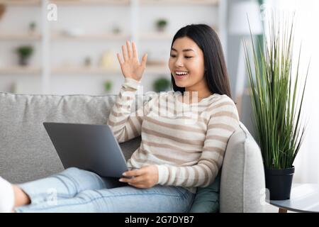 Fröhlich Jung Asiatisch Weiblich Machen Video-Anruf Mit Laptop Zu Hause Stockfoto
