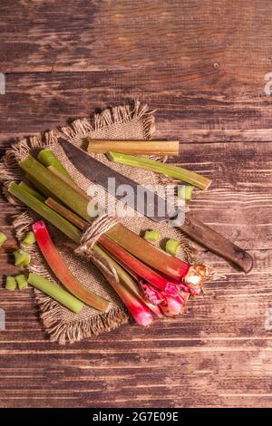 Frische Rhabarberstiele und geschnittene Stücke auf einem Vintage-Holztisch. Gesunde Zutat, Kochen nützliche Lebensmittel-Konzept, Draufsicht Stockfoto