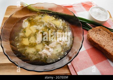 Suppe aus Sauerampfer, grünen Zwiebeln und Eiern wird auf einen Teller gegossen Stockfoto