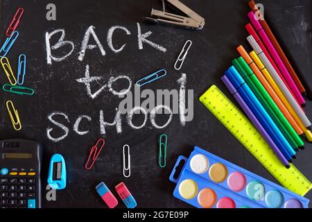 Die Inschrift zurück zur Schule auf der Tafel unter den Schulvorräten Stockfoto