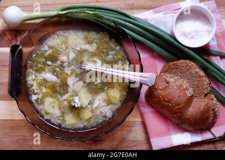 Suppe aus Sauerampfer, grünen Zwiebeln und Eiern wird auf einen Teller gegossen Stockfoto